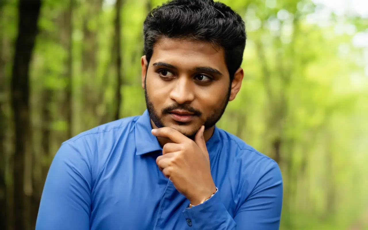 Indian male thinking traying to make a choice in a blur forest background